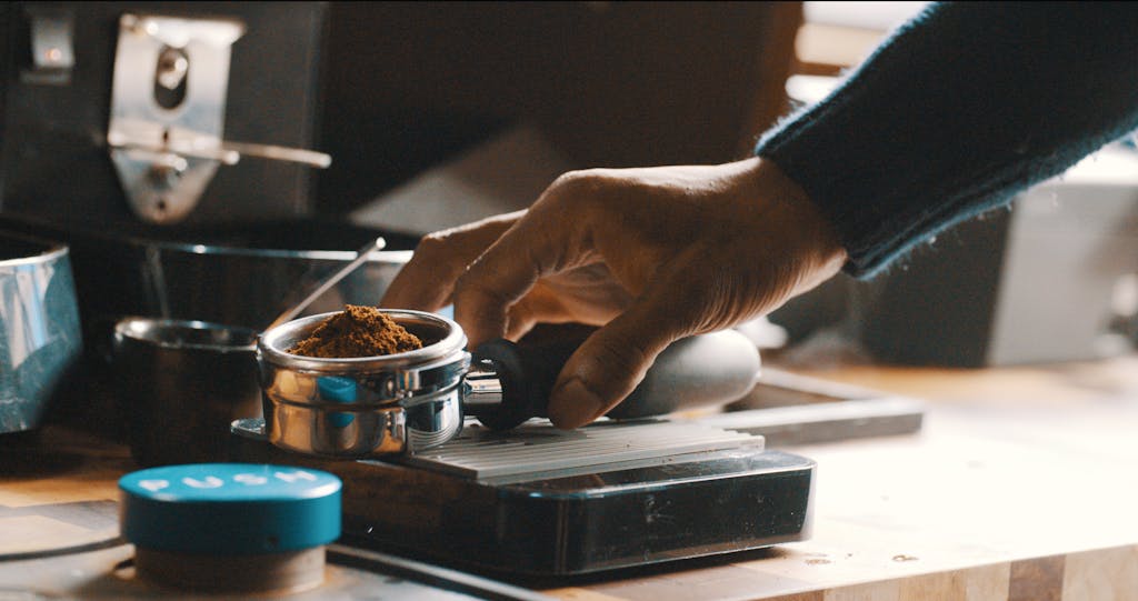 Close-up of a barista's hand preparing coffee grounds with precision in a modern kitchen.