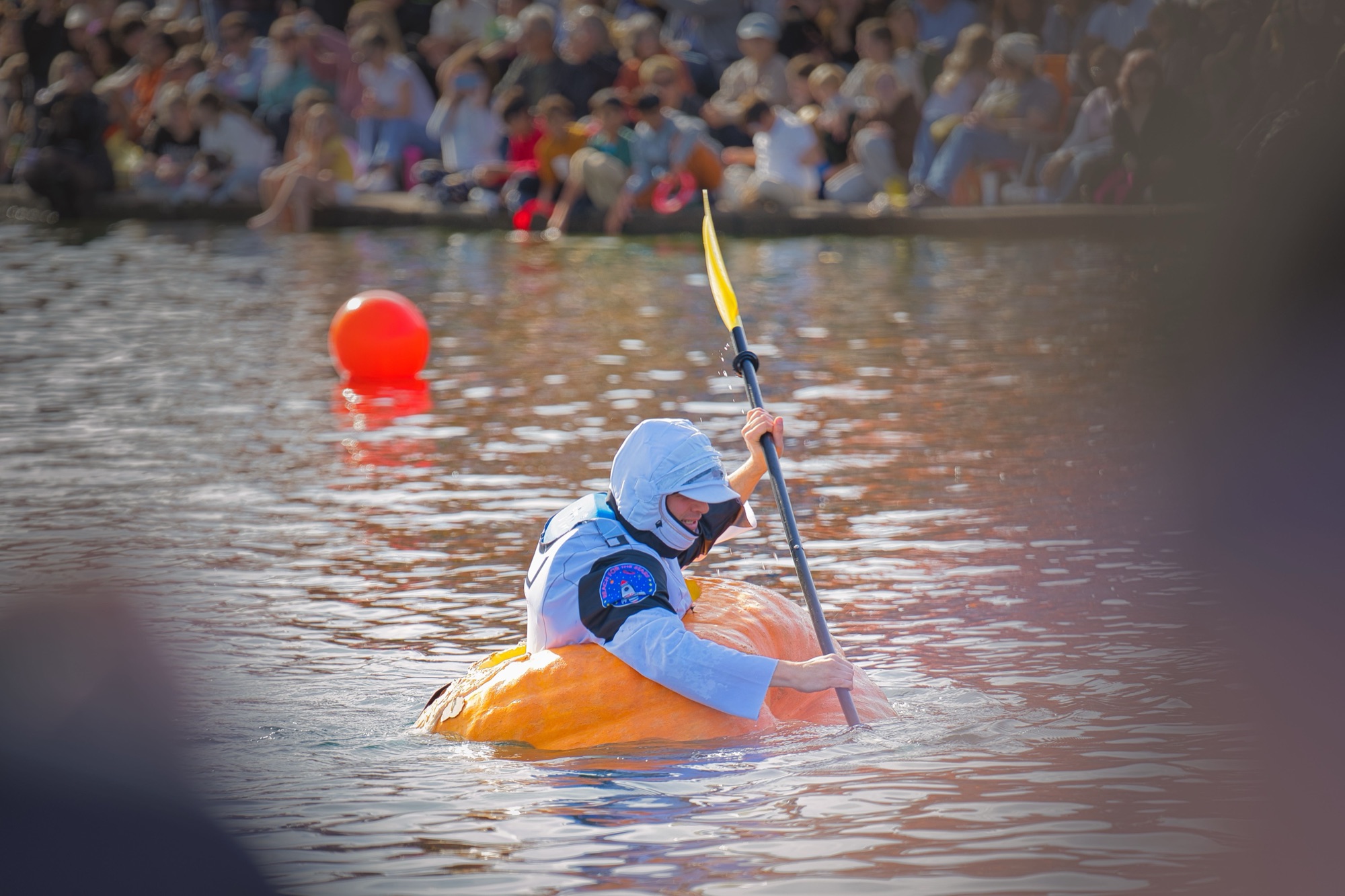 A paddler in an astronaut costume in a giant pumpkin