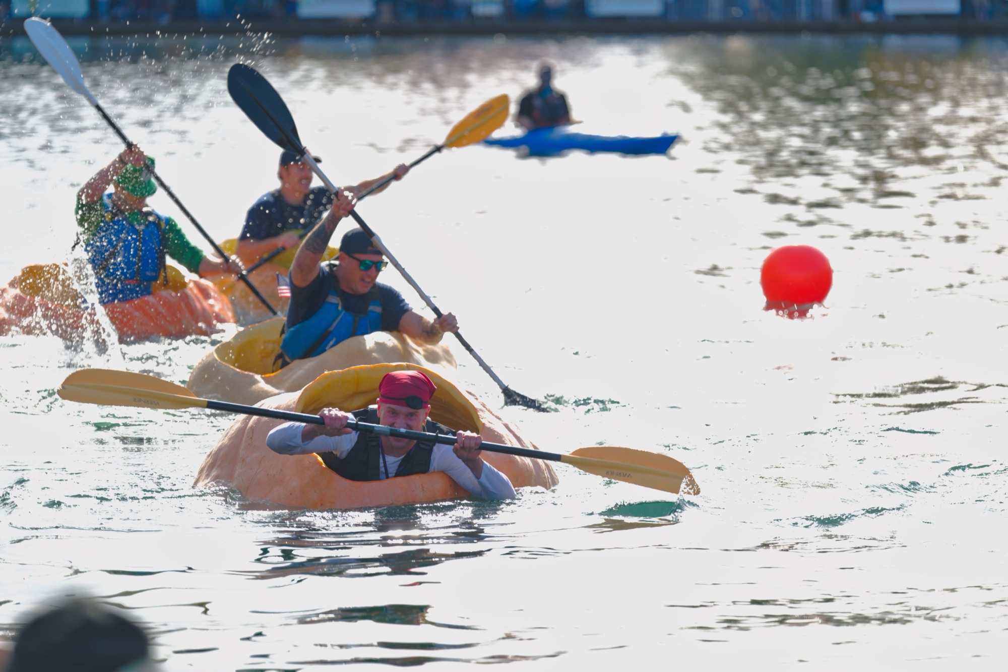 A paddler in a red pirate bandana leaning forward to stay ahead of the pack in a giant pumpkin