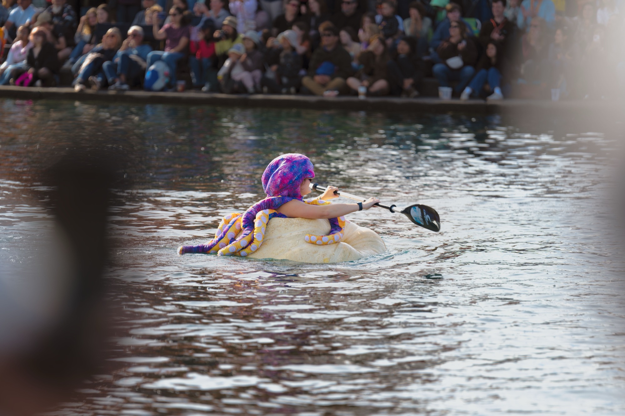 A paddler in an octopus costume with tentacles draped over the rim of a giant pumpkin